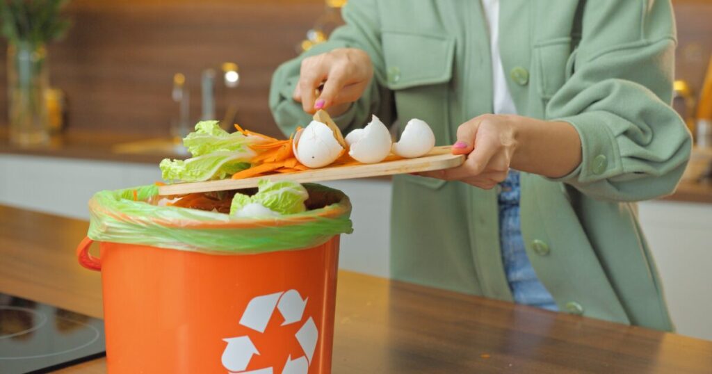 卵の殻や野菜くずを生ごみ回収容器に捨てる様子