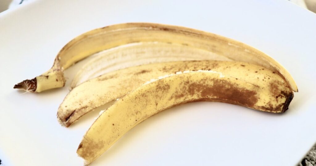 白い皿に置かれた熟したバナナの皮の食品廃棄物